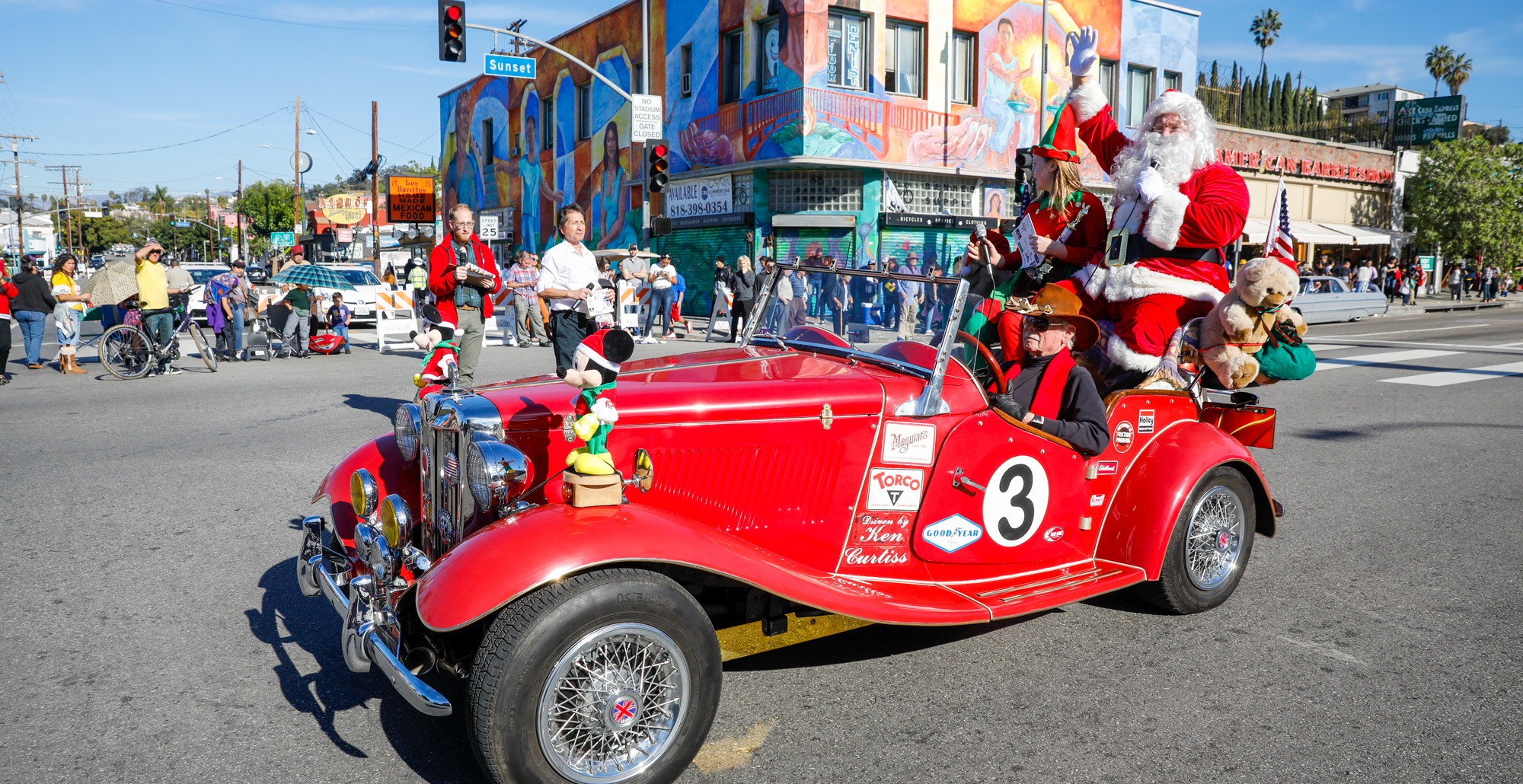 Santa in a classic red car at a holiday parade